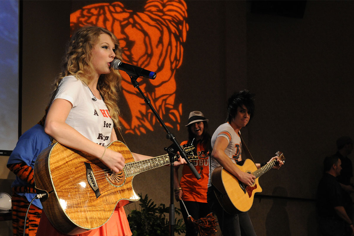 Taylor Swift performing with her guitar at the surprise Auburn concert